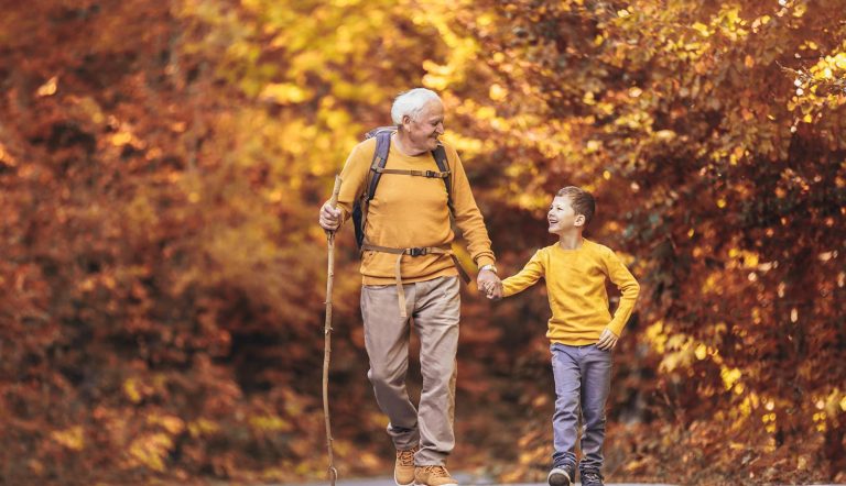 Grandfather and grandson hiking together in autumn park